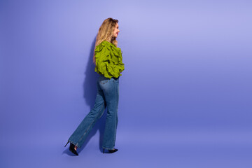 Charming young woman in lime green blouse walks stylishly against a purple background