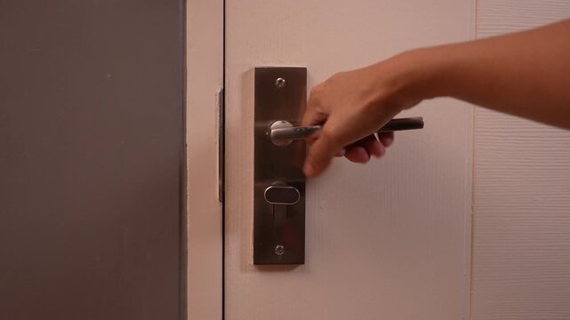 Close-up of hand rattling and shaking a locked bedroom door handle, trying to open the door but it is stuck, suspenseful and mystery atmosphere, trapped inside a room concept.