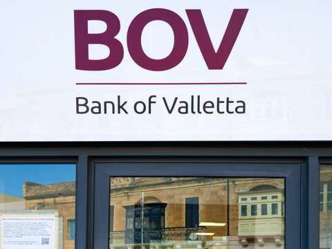 Marsaxlokk , Malta, December 12, 2025 - Bank of Valletta logo on glass facade with reflection of traditional buildings