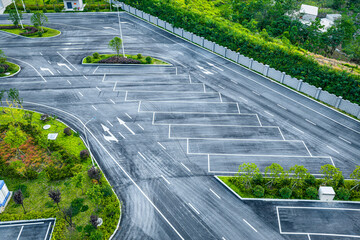 High angle view of an empty asphalt parking lot with white directional arrows and line markings in a modern facility. © zhao dongfang