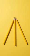 Yellow Pencils Arranged in a Triangle on a Bright Yellow Background for Creative Projects