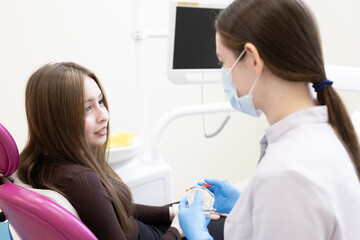 Obraz premium The patient is afraid of the dentist and covers her mouth with her hands. woman sitting in dental chair