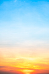 Obraz premium Sunset or sunrise sky with a vibrant gradient of orange, gold, and soft blue. Clear atmosphere with wispy clouds. Peaceful, natural light background. hope, freedom, new day Concepts, Vertical