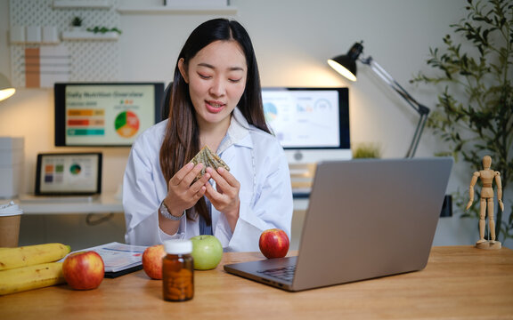 Healthy lifestyle consultant working on a laptop and reviewing nutrition charts in a bright workspace.