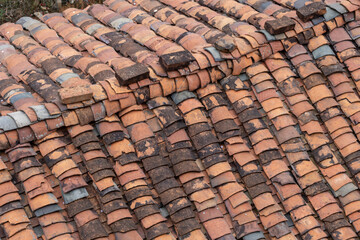 Fototapeta premium Close-up view of aged terracotta roof tiles arranged in overlapping rows, showing weathering, discoloration. The textured clay surface reflect traditional construction methods in rural China.