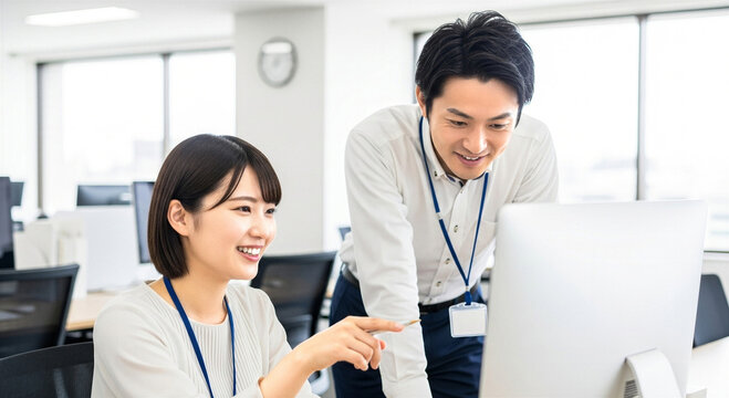 オフィスで相談する男女の会社員 パソコン操作 笑顔 打ち合わせ 教育 指導 上司 部下 日本人