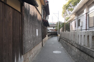 Obraz premium Traditional Japanese Narrow Alley with Historic Wooden Walls and Tiled Roof Fences. Authentic Kyoto Style Streetscape Featuring Vernacular Architecture and Old Neighborhood Atmosphere in Japan.