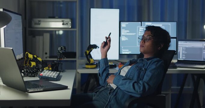 Young African American female programmer coding AI software on multiple screens in night office. Network security, cybersecurity, machine learning, working late, overtime, robotics automation concept.