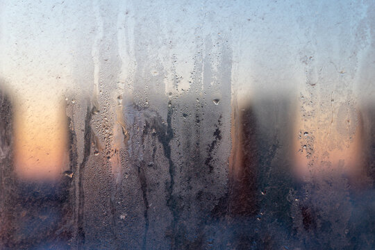 Dirty and dusty dark window glass in the sunset. Abstract dirty window glass background. Window with very dirty and dusty glass in daylight in the sunset. Condensation on the fogged windows glass. 