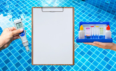 Swimming pool water testing test kit with blank report paper on wooden clipboard over clear pool water background, quality water tester technology