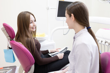 Fototapeta premium A dentist consults a patient with a dental x-ray. A dentist shows a patient an X-ray