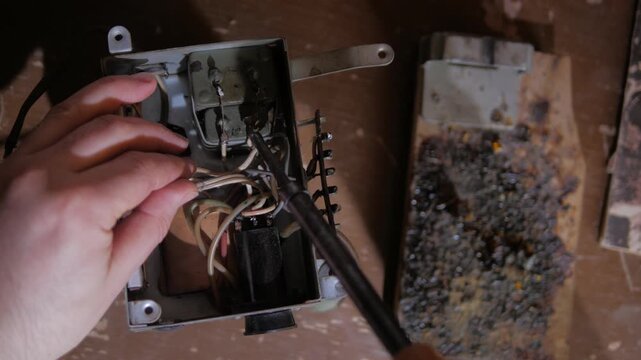 man checks the wire connection on an old radio amplifier