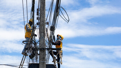 Technician sorting through a chaotic tangle of electrical and internet wires on a concrete pole.