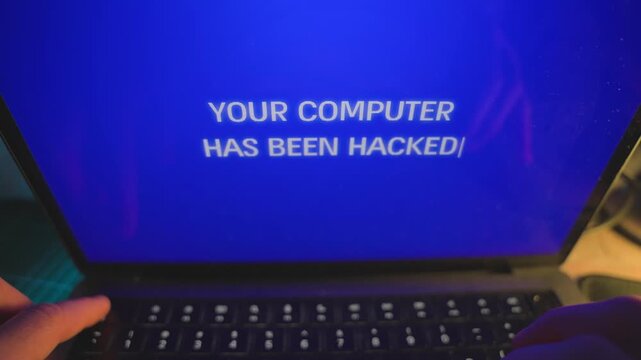Close up on laptop screen with message alert of dangerous hacker attack. Man surprised and panic when computer announces hacker taking over control and locking and blocking usage disabling keyboard