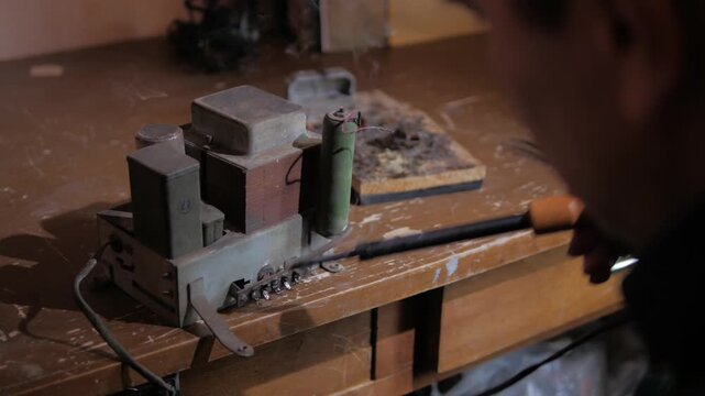 repairing contacts on an old radio amplifier using a soldering iron close-up
