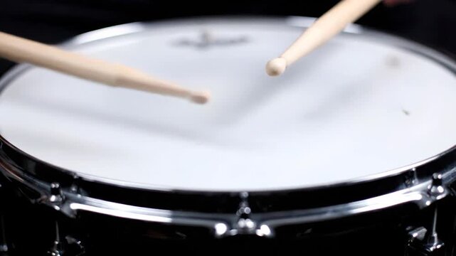 Powerful close-up of wooden drumsticks poised over a bright snare drum head, ideal for music education content and band promotion videos.