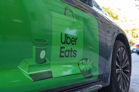 Uber Eats logo displayed on a delivery car door parked outside