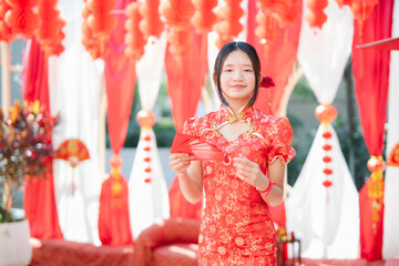 Obraz premium The celebration of Chinese New Year traditions: a young woman in a red qipao (traditional Chinese dress) holding a red envelope.
