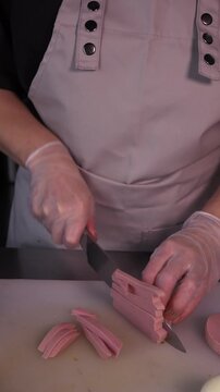 The cook cuts the sausage for the salad. Preparation of appetizers and salads