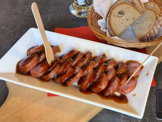 Sliced ​​fried sausage with wooden forks. Close-up