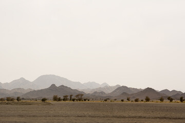 Obraz premium Desert landscape with multiple layers of hills and mountains fading into haze creating depth atmosphere and a sense of vastness in an arid environment