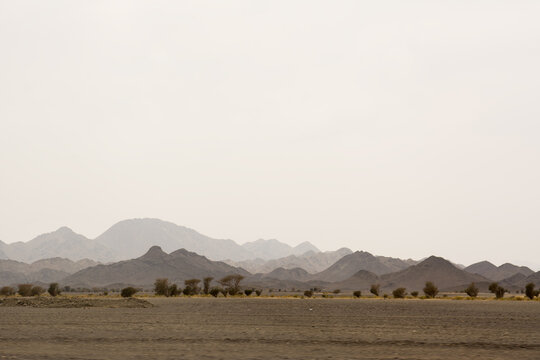 Desert landscape with multiple layers of hills and mountains fading into haze creating depth atmosphere and a sense of vastness in an arid environment