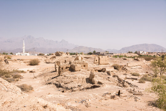 Ruins of an ancient abandoned city with a white mosque minaret in the background in Saudi Arabia