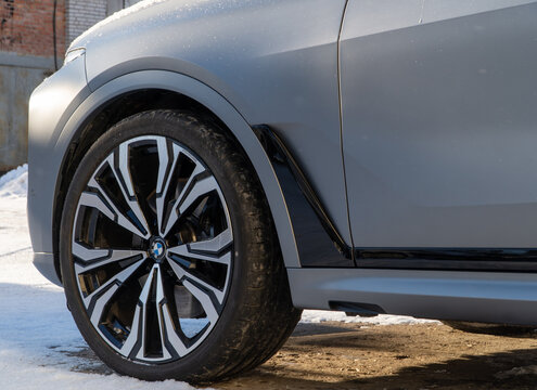 Metallic gray BMW X7 G07 in the street parking lot. The modern vehicle exterior SUV car BMW X7 G07. Premium Germany SUV Car BMW X7 G07 covered snow in the street parking.