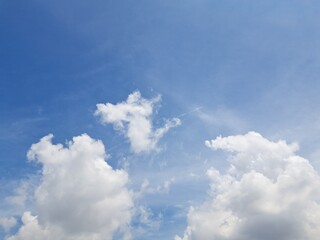 Obraz premium Afternoon sky filled with clouds, illuminated by the bright afternoon sun – White and grey clouds illuminated by the rays of the afternoon sun, amidst a blue sky.