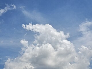 Obraz premium Afternoon sky filled with clouds, illuminated by the bright afternoon sun – White and grey clouds illuminated by the rays of the afternoon sun, amidst a blue sky.