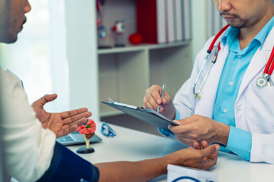 The doctor is showing the patient an anatomical model of the brain. A neurologist is examining the patient's head to specifically assess his brain health.