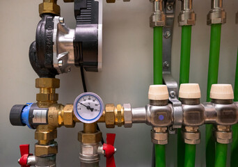 Modern home plumbing and heating system components. Close-up of a circulating pump, manifold, valves, and pressure gauge. Ideal for HVAC, installation, maintenance, energy efficiency.