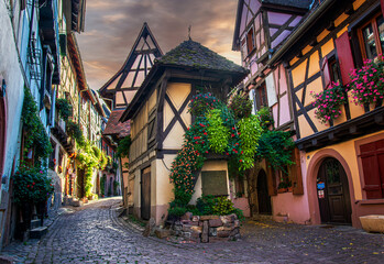 Fototapeta premium Narrow street in old city of Eguisheim, Alsace, France. Beautiful colorful half-timbered houses. Place in Alsace, an authentic fairytale place, one of most beautiful village of France
