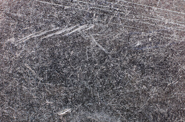 Close-up texture of a scratched and weathered dark metallic surface with fine details