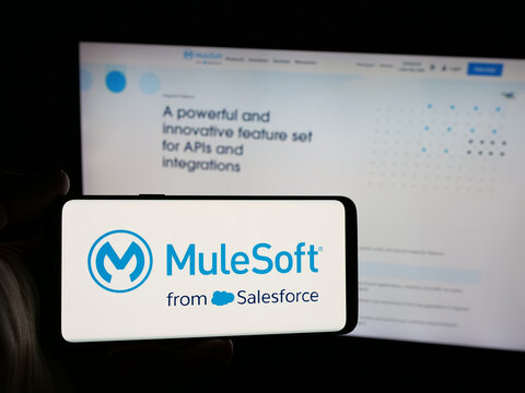 Stuttgart, Germany - 01-26-2026: Person holding smartphone with logo of US integration software company MuleSoft LLC on screen in front of website. Focus on phone display.
