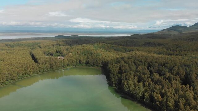 Aerial view of backwards flight above Edmonds Lake with little house in Alaskan wilderness