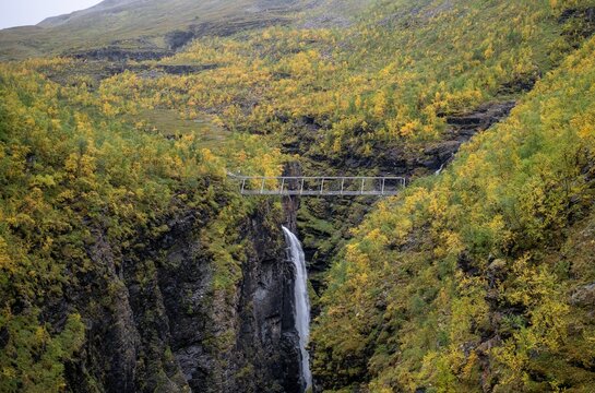 Autumn waterfall canyon with Gorsa Bridge above deep gorge in Norway