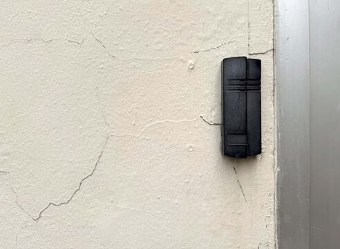 Black electronic card reader access control on cracked concrete wall.