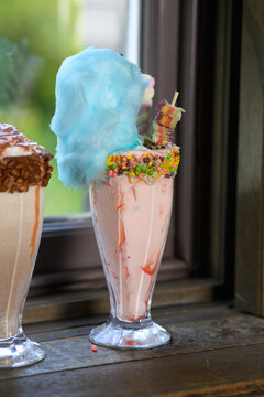 A glass of pink drink with a blue top and a blue straw