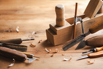Carving and woodworking tools on wooden workbench in carpentry workshop. Wood processing and joinery work.