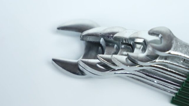 Rotating close-up of chrome open-end wrenches stacked in precision alignment. Clean studio lighting highlights metal texture, durability, and professional tool quality.