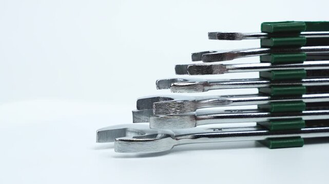 Rotating open-end wrenches arranged in layered formation on white. Highlights clean geometry, reflective metal, and professional tool quality.