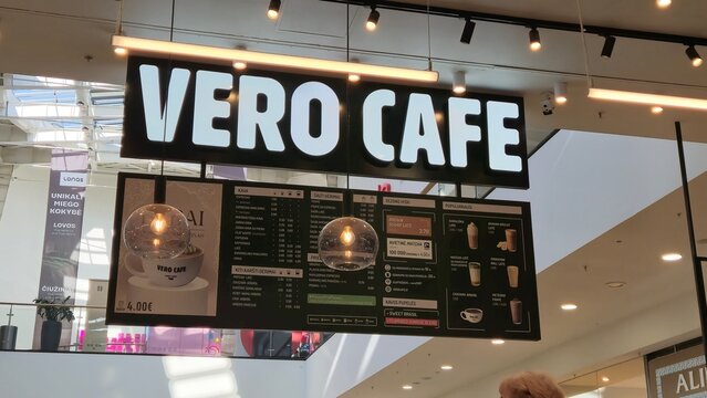 Vilnius Lithuania - 03.29.2025 Vero Cafe illuminated sign and hanging menu displaying coffee and drink options including espresso, latte, matcha, and seasonal items in a shopping mall food court