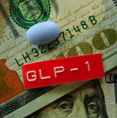 A GLP-1 pill and red label on US hundred dollar bills