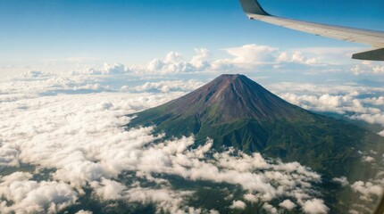 Majestic Volcano Peak Emerges From Fluffy White Clouds Seen From Airplane Window Above Lush Green Forest Below Bright Blue Sky