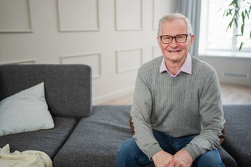 Fototapeta premium Portrait of confident stylish European middle aged senior man at home. Older mature 70s man smiling. Happy attractive senior grandfather looking camera close up face headshot portrait. Happy people