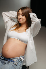 A pregnant woman gently holds her rounded belly in her hands. A warm and touching moment