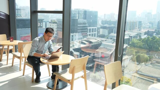A man working on a tablet computer by the window in a modern urban caf&eacute;