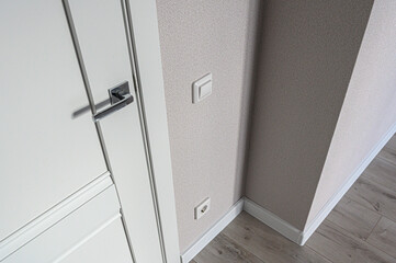 A white interior door with a sleek metallic handle; light beige textured walls with white...