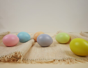 Easter decoration with eggs. Colorful pastel eggs arranged on a burlap cloth with neutral background for Easter decoration. Easter concept. Pro Photo